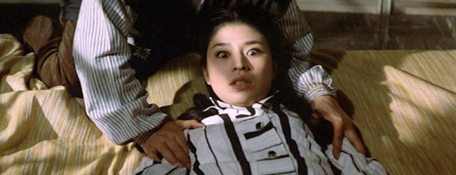 Keiko (Kayo Matsuo) is held down by Genzo while Dr. Yamaguchi approaches her with a hypodermic needle.