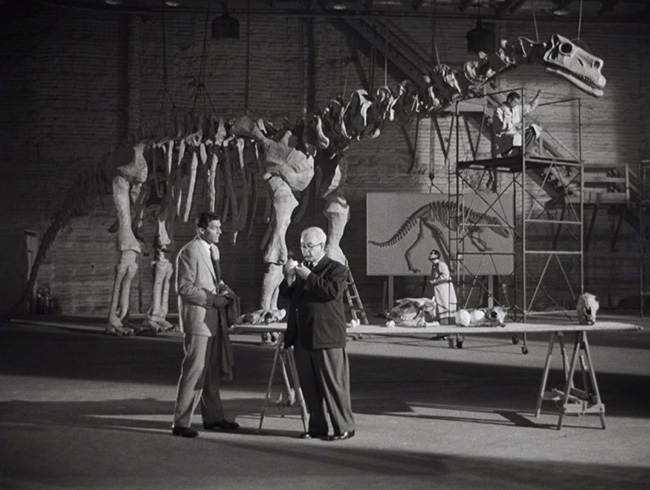 Prof. Thomas Nesbitt (Paul Hubschmid) describes the Rhedosaurus to Prof. Thurgood Elson (Cecil Kellaway). The skeleton in the background was borrowed from "Bringing Up Baby."