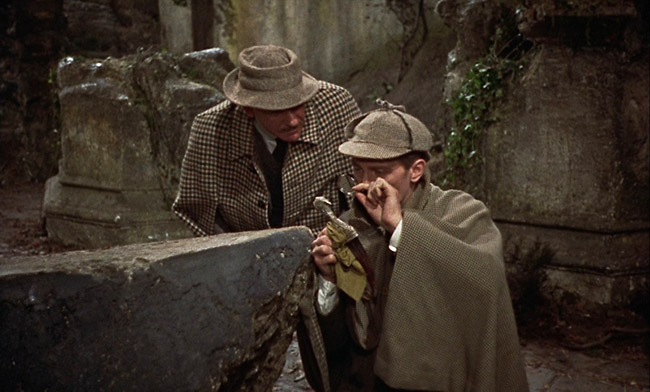 Sherlock Holmes (Peter Cushing) examines a dagger while Dr. Watson looks on.